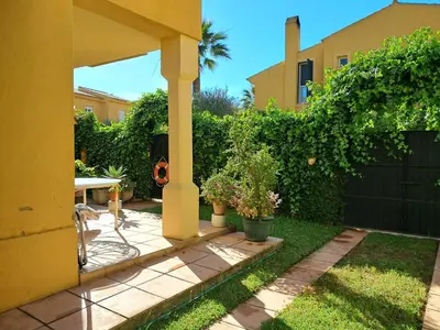 a backyard with a yellow house and a fence at Casa playa El Ancla Puerto Santa María in El Puerto de Santa María
