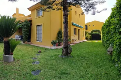 a yellow house with a palm tree in the yard at Casa playa El Ancla Puerto Santa María in El Puerto de Santa María