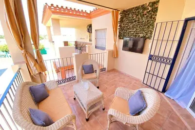 a balcony with wicker chairs and a table and a tv at Apartamento Camaleón in Chipiona