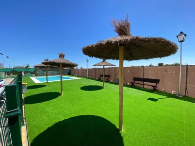 a group of umbrellas on a lawn with a pool at Apartamento Camaleón in Chipiona