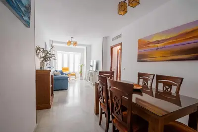 a dining room and living room with a table and chairs at Lightbooking América I Sanlúcar de Barrameda in Sanlúcar de Barrameda