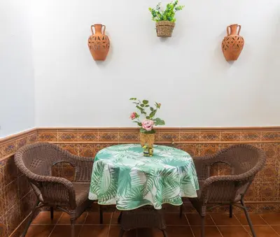 a table with chairs and a vase with flowers on it at Lightbooking América I Sanlúcar de Barrameda in Sanlúcar de Barrameda