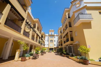 a courtyard of apartment buildings with benches and potted plants at Lightbooking América I Sanlúcar de Barrameda in Sanlúcar de Barrameda