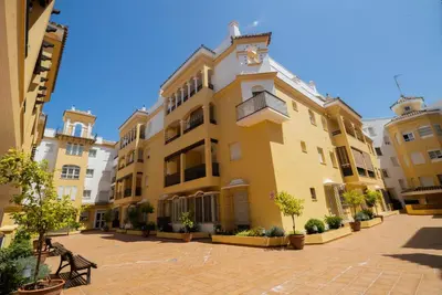a large yellow building with trees in a courtyard at Lightbooking América I Sanlúcar de Barrameda in Sanlúcar de Barrameda