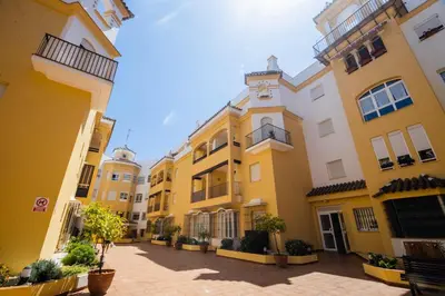 a row of yellow buildings with a clock at Lightbooking América I Sanlúcar de Barrameda in Sanlúcar de Barrameda