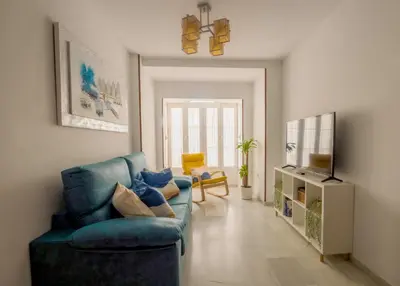 a living room with a blue couch and a television at Lightbooking América I Sanlúcar de Barrameda in Sanlúcar de Barrameda