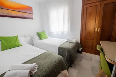 a room with two beds and a table and a desk at Lightbooking América I Sanlúcar de Barrameda in Sanlúcar de Barrameda