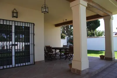 a patio with a gate and a table and chairs at Moderno y amplio chalet, con piscina privada in Chiclana de la Frontera