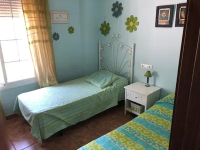 a small bedroom with two beds and a night stand at Moderno y amplio chalet, con piscina privada in Chiclana de la Frontera