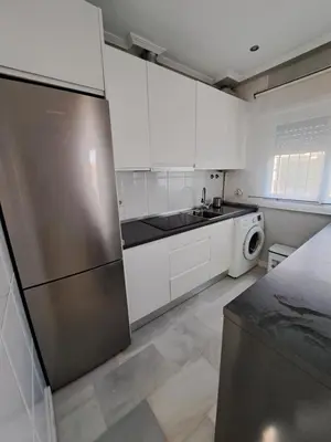a kitchen with white cabinets and a stainless steel refrigerator at Apartamento Pinares del atlantico in Chiclana de la Frontera