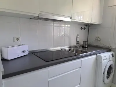 a kitchen with a sink and a washing machine at Apartamento Pinares del atlantico in Chiclana de la Frontera