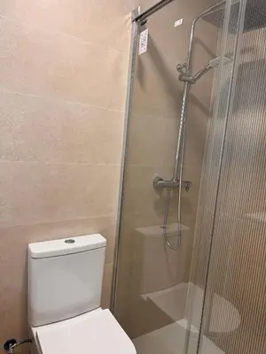 a bathroom with a toilet and a glass shower at Apartamento Pinares del atlantico in Chiclana de la Frontera