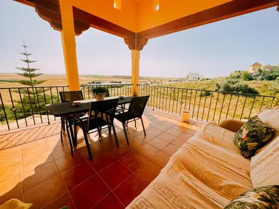 a living room with a table and chairs on a balcony at DeCapi House in Sanlúcar de Barrameda