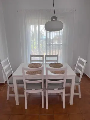 a white dining room table with four chairs and a light fixture at Casa de Fernando in Puerto Real