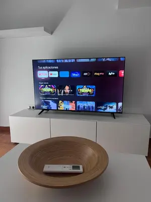 a flat screen tv on a white stand with a remote control at Casa de Fernando in Puerto Real