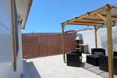 a patio with a wooden pergola and chairs at Casa de madera muy acogedora en una zona tranquila in Chiclana de la Frontera
