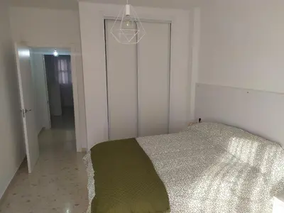 a white bedroom with a bed and a chandelier at Casa Julia in Sanlúcar de Barrameda