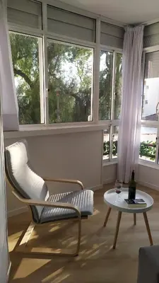 a living room with a chair and a table and windows at Casa Julia in Sanlúcar de Barrameda