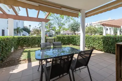 a patio with a glass table and chairs at Apartamento Planta Baja Coto Sancti Petri Playa de la Barrosa in Chiclana de la Frontera