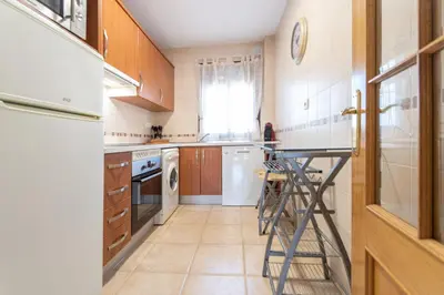 a kitchen with white appliances and a table in it at Apartamento Planta Baja Coto Sancti Petri Playa de la Barrosa in Chiclana de la Frontera