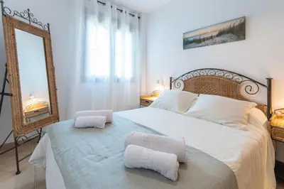a bedroom with a large white bed with towels on it at Apartamento Planta Baja Coto Sancti Petri Playa de la Barrosa in Chiclana de la Frontera