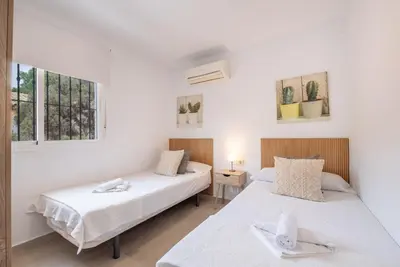 two beds in a room with two windows at Villa Empul La Caracola in Chiclana de la Frontera