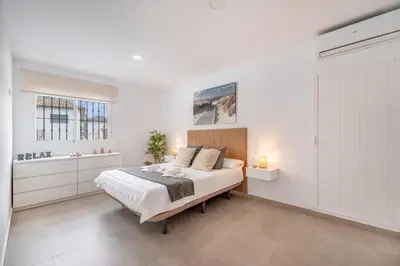 a white bedroom with a bed and two windows at Villa Empul La Caracola in Chiclana de la Frontera