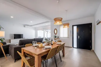 a dining room and living room with a table and chairs at Villa Empul La Caracola in Chiclana de la Frontera