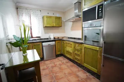 a kitchen with wooden cabinets and a stainless steel refrigerator at Casa PauMar, tu casa en Arcos de la Frontera in Arcos de la Frontera