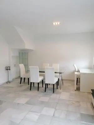 a dining room with white chairs and a table at Casa con piscina privada in El Puerto de Santa María