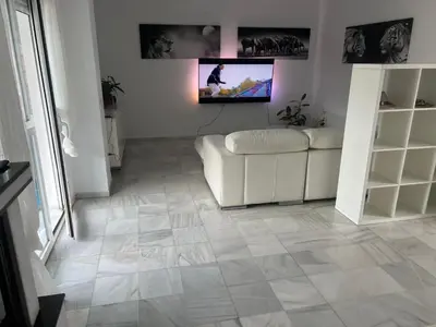 a living room with a couch and a tv on the wall at Casa con piscina privada in El Puerto de Santa María