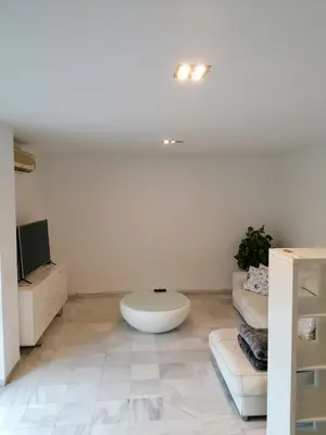 a white living room with a white couch and a tv at Casa con piscina privada in El Puerto de Santa María