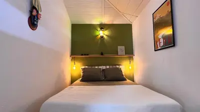 a small bed in a room with a green wall at Arriba stijlvol appartement met zwembad en tuin in Conil de la Frontera