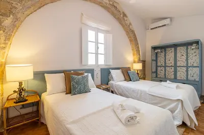 a room with two beds and a window at Ático La Casa Rosa - Parking opcional in Jerez de la Frontera