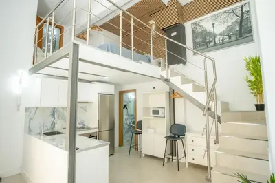 a room with a staircase and a kitchen with stools at MARÍTIMO28 in Cádiz