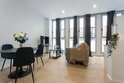 a living room with a table and chairs and windows at LalaSuites RIANAL in Jerez de la Frontera
