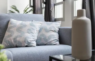a gray couch with pillows and a white vase on a table at LalaSuites RIANAL in Jerez de la Frontera