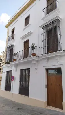 a white building with a brown door and windows at Sherryflat Arroyo in Jerez de la Frontera