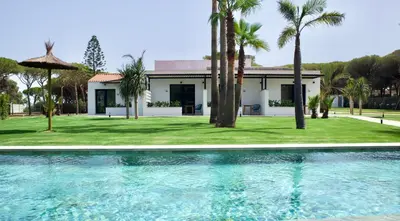 a villa with a swimming pool in front of a house at Alojamiento rural FINCA AZUCENA SUITE only adults in Conil de la Frontera
