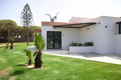 a white house with a yard with palm trees at Alojamiento rural FINCA AZUCENA SUITE only adults in Conil de la Frontera