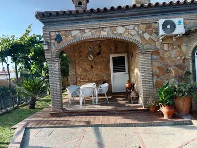 a patio with white chairs and a stone building at Chalet Villa Terry in Chiclana de la Frontera