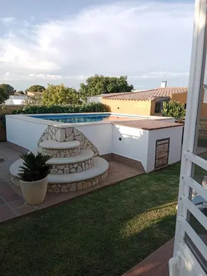 a backyard with a swimming pool and a patio with chairs at Chalet Villa Terry in Chiclana de la Frontera