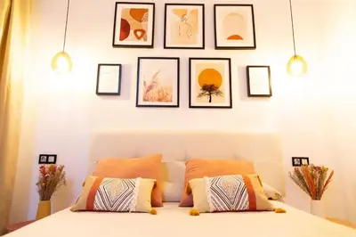 a bedroom with a bed with framed pictures on the wall at La Gloria in Cádiz