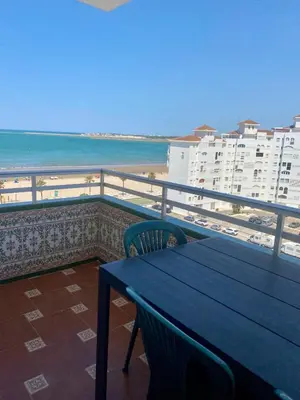 a blue table and chairs on a balcony with the beach at APARTAMENTO VISTAS AL MAR - Valdelagrana Playa in El Puerto de Santa María