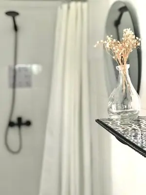 a glass vase with flowers on a shelf in a bathroom at Alojamiento rural CASAPIÑA in Conil de la Frontera