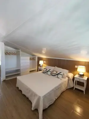 a large white bed in a room with two tables at Apartamento Mistral 5, con piscina y parking. in Chiclana de la Frontera