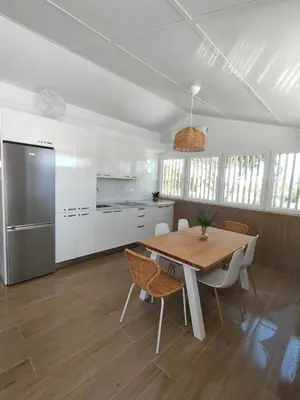 a kitchen with a table and chairs and a refrigerator at Apartamento Mistral 5, con piscina y parking. in Chiclana de la Frontera