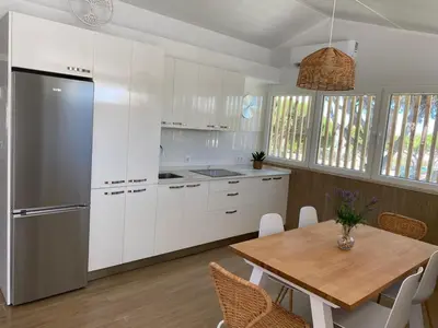 a kitchen with white cabinets and a wooden table at Apartamento Mistral 5, con piscina y parking. in Chiclana de la Frontera