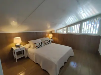 a bedroom with a large bed with two tables and two windows at Apartamento Mistral 5, con piscina y parking. in Chiclana de la Frontera