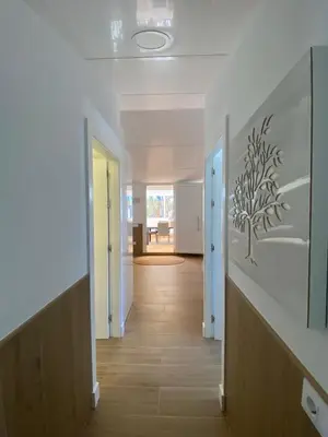a hallway with white walls and wooden floors and doors at Apartamento Mistral 5, con piscina y parking. in Chiclana de la Frontera